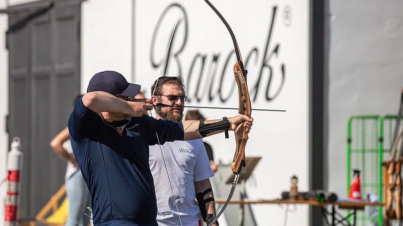 Zwei Männer und einer von Ihnen Spannt ein Bogen