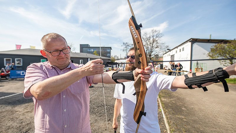 Mann zeigt einen anderen man wie man ein Bogen spannt