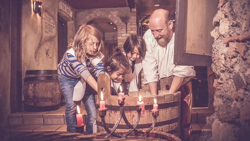 Mann zeigt Kindern wie in die Hände im Mittelalter gewaschen worden sind