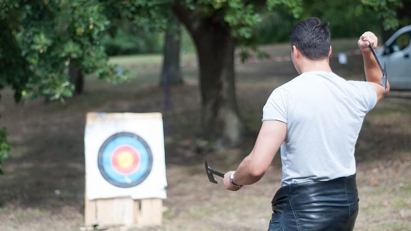 Mann zielt mit einer Axt auf eine Zielscheibe.
