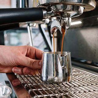 Barista-Basic-2.jpg man sieht eine Siebträgermaschine, die einen Behälter mit Kaffee befüllt- Barista Basic Schulung in Dresden