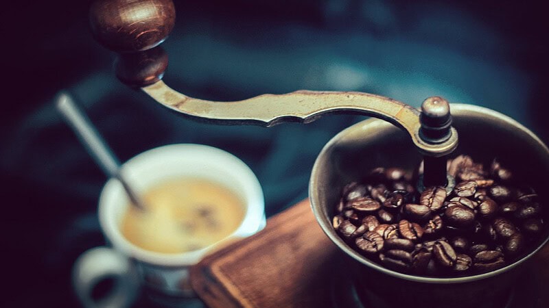 man sieht eine altmodische Kaffeemühle mit Bohnen befüllt.- Barista Basic Schulung in Dresden