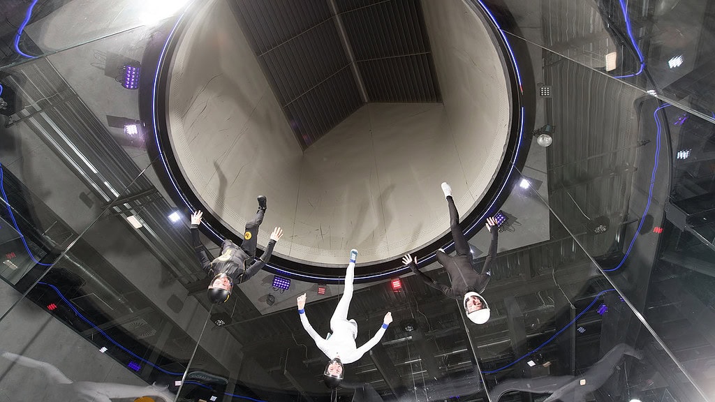 Bodyflying-bei-Berlin-_12.jpg Drei Personen fliegen kopfüber im Windkanal während des Bodyflying bei Berlin