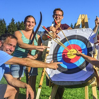 Bogenschiessen-Dresden.jpg Gruppe von Männer und Frauen vor einer Zielscheibe beim Bogenschießen in Dresden
