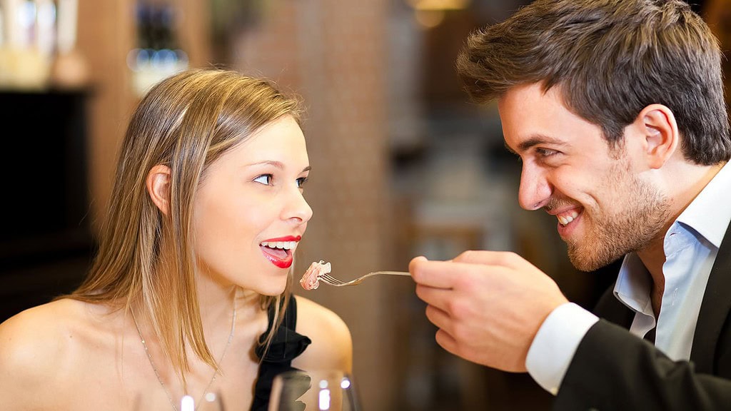 Romantic couple having dinner, man feeding woman Paar füttert sich selbst