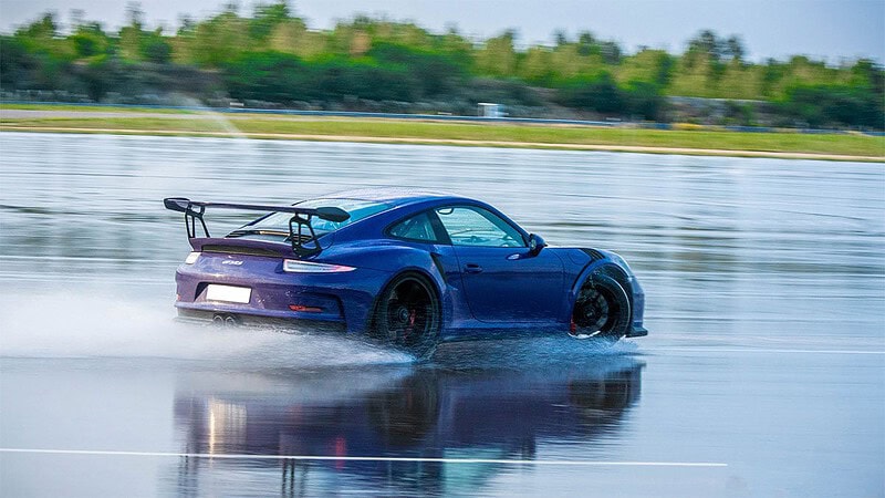 Ein Porsche driftet auf einer nassen Fahrtbahn auf dem Lausitzring.