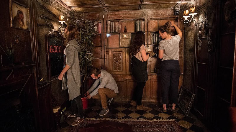 Menschen suchen im Raum nach Hinweisen beim Escape Room - Virtual Reality (VR) in Berlin