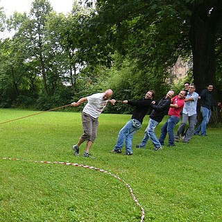 Gruppe spannt bei der Team Challenge Schnitzeljagd ein Seil an dem ein Mensch hängt