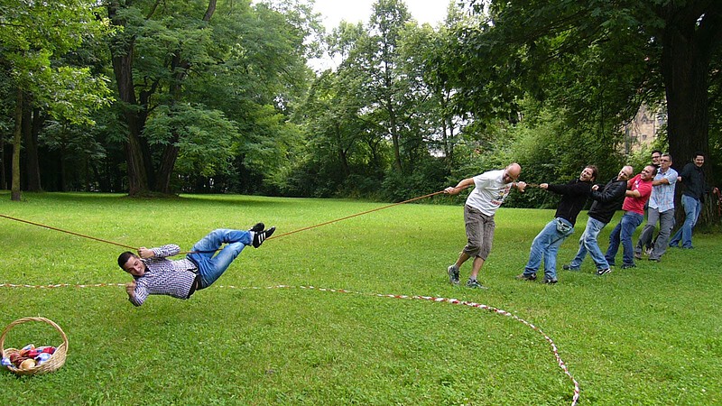 Gruppe spannt bei der Team Challenge Schnitzeljagd ein Seil an dem ein Mensch hängt