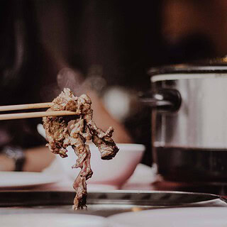 Frau isst Fleisch mit Stäbchen