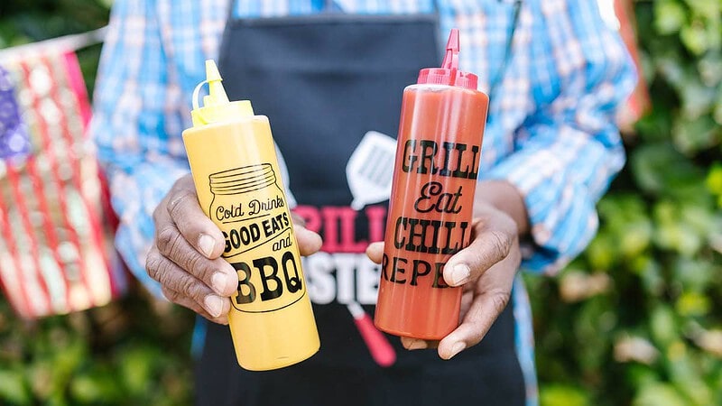 Ein Mann hält Ketchup und Senf in der Hand