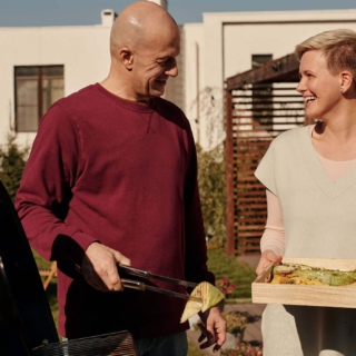 Ein Mann und eine Frau lachen und grillen Gemüse zusammen