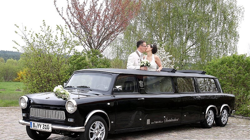Brautpaar schaut aus dem Verdeck der Hochzeitstrabant Stretchlimousine und küsst sich