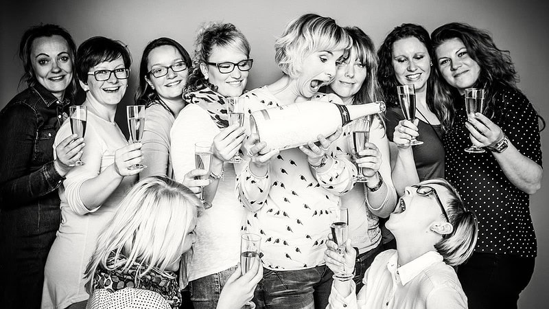 Viele Frauen mit Sektgläsern, eine schenkt aus einer großen Flasche aus