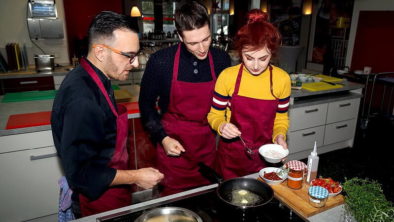 drei Menschen vor Herdplatte beim Kochkurs in Dresden