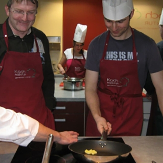 Personen stehen am Herd zum Kochkurs in Dresden