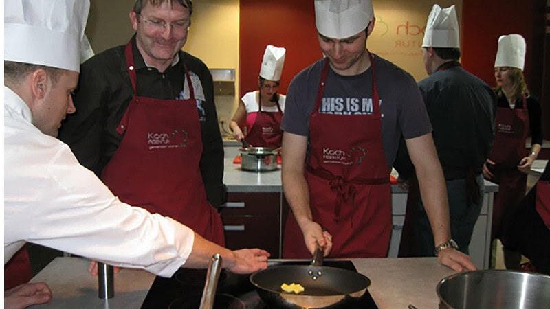 Personen stehen am Herd zum Kochkurs in Dresden