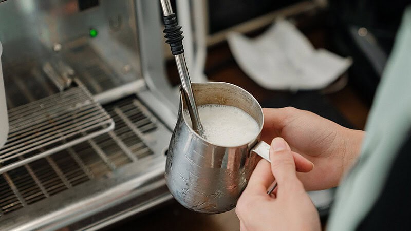Ansicht einer Kaffeemaschine, dass eine Kanne Milch aufschäumt- Barista Latte Art Schulung in Dresden