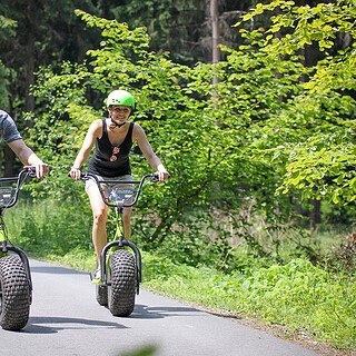 Frau und Mann auf einem Waldweg aug dem Monsterroller unterwegs