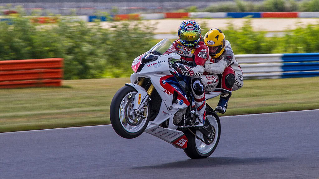 Motorrad-Renntaxi-Superbike-Doppelsitzer_5-1.jpg 2 Personen fahren auf einem Fahrrad zusammen und machen Wheelie
