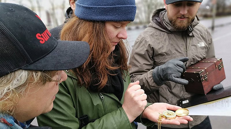 Kleine Gruppe mit Kiste und Kompass in der Hand.