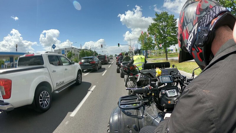 Quads stehen auf einer Straße an einer Ampel auf der linken Seite Autos.