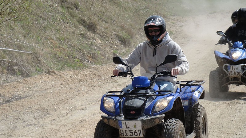 Mann fährt bei Quadtour einen Sandweg entlang