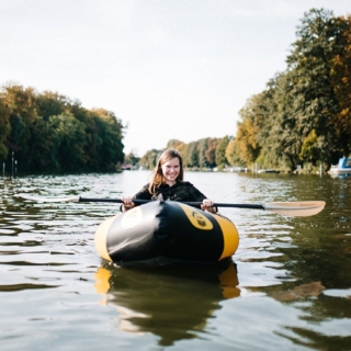 Schlauchboot mieten - Packraft auf dem Wasser mit Frau, die in die Kamera schaut und lächelt
