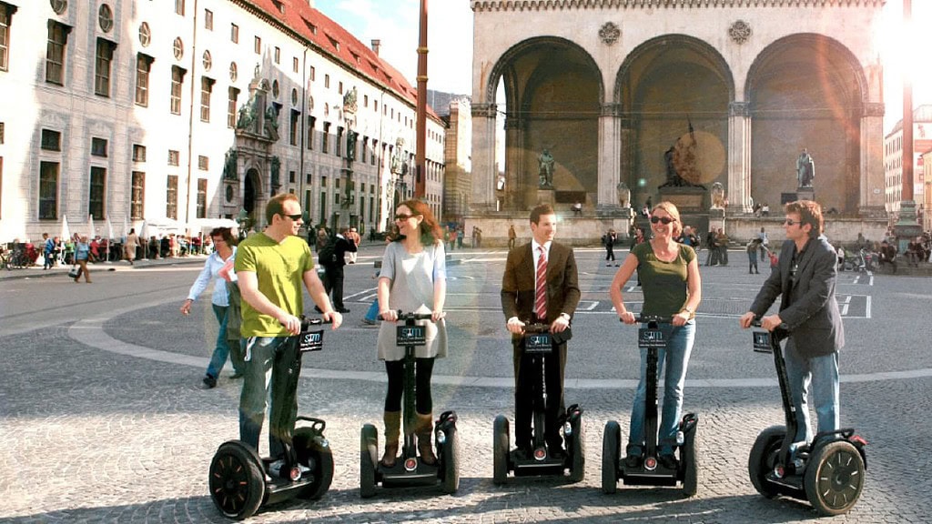 Fünf Menschen stehen mit Segways auf einem Platz