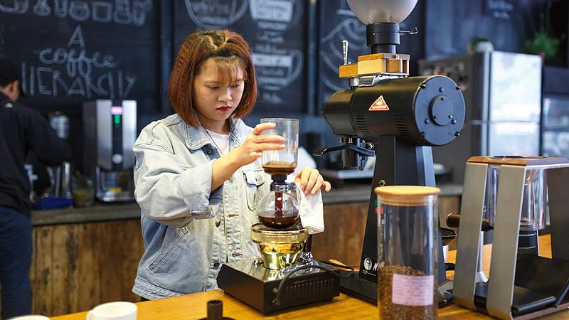 Man sieht eine Frau, die gerade Kaffee durch einen durch Behälter filtert- Sensorikkurs mit Cupping in Dresden