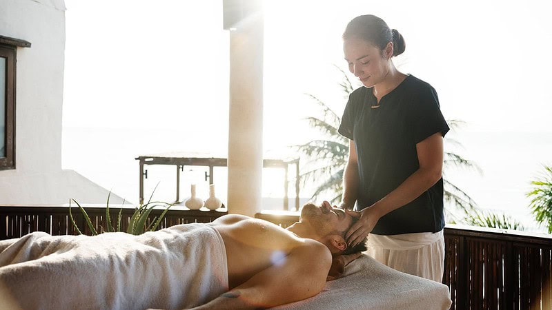 Frau massiert Mann den Kopf mit einer Lomi Lomi Massage in Chemnitz