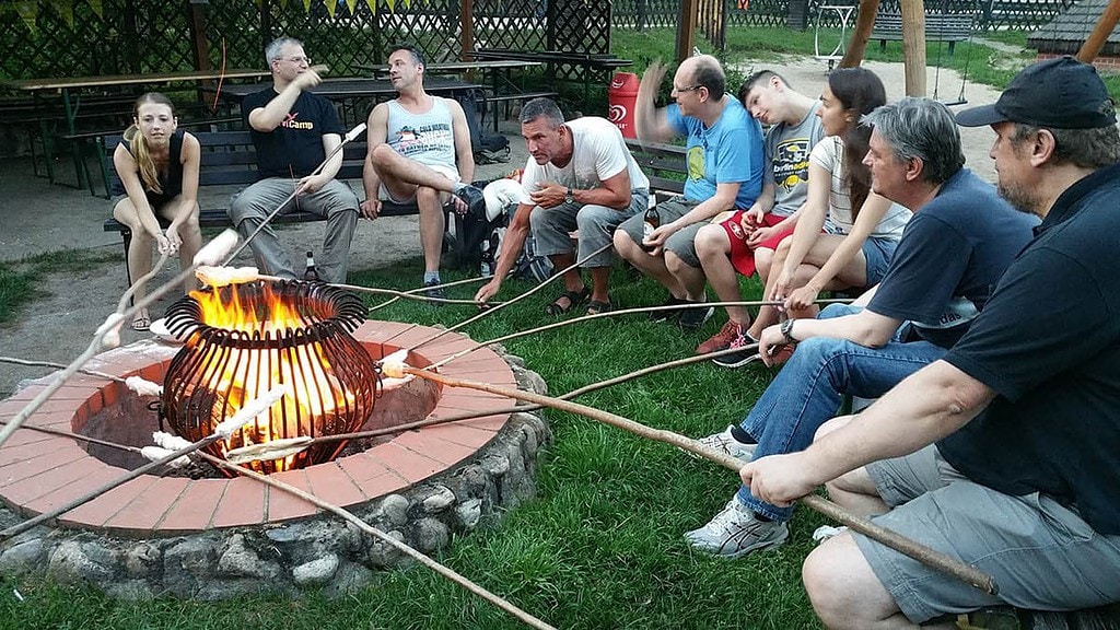 Gruppe sitzt um ein Feuer im Kreis mit Stockbrot.