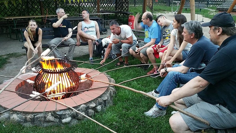Gruppe sitzt um ein Feuer im Kreis mit Stockbrot.