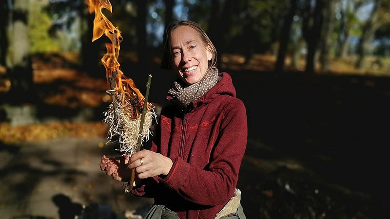 Frau hält Brennende Holzwolle vor sich.