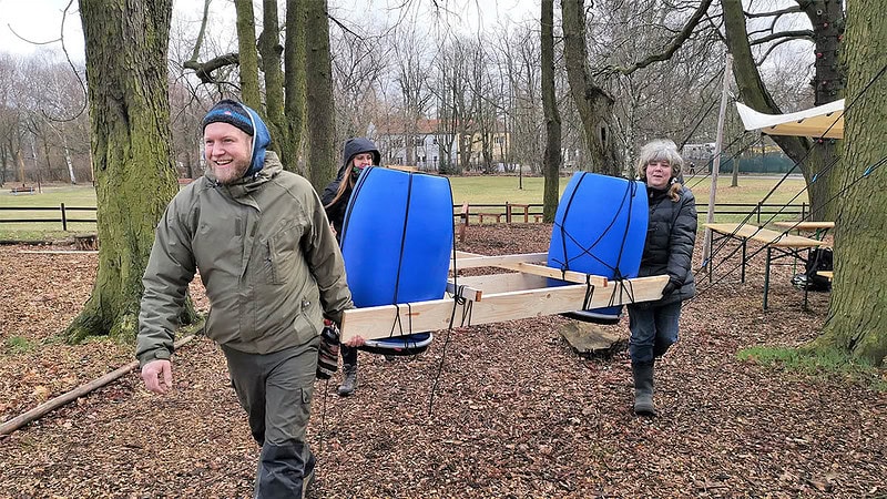 Gruppe trägt das Floß durch den Wald