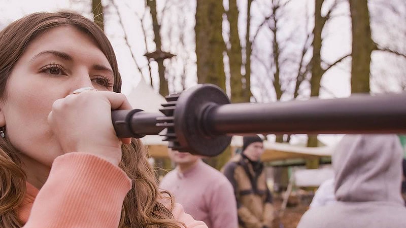 Frau beim Blasrohr-Schießen.