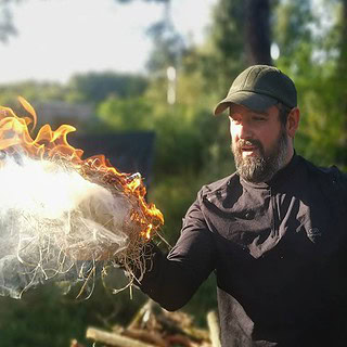 Mann hält ein Brennendes Holzwollknäul in der Hand.