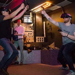 2 Männer spielen mit einer VR Brille in einem Raum