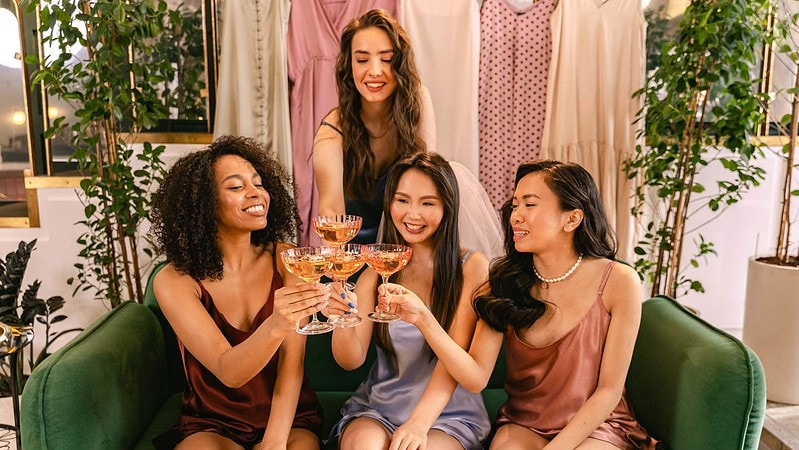 Vier Frauen sitzen auf einem Couch, trinken gemeinsam Rosewein und feiern