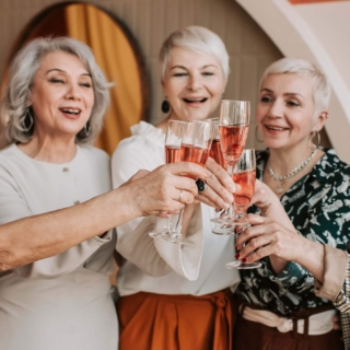 Fünf Frauen trinken gemeinsam Rosewein und feiern
