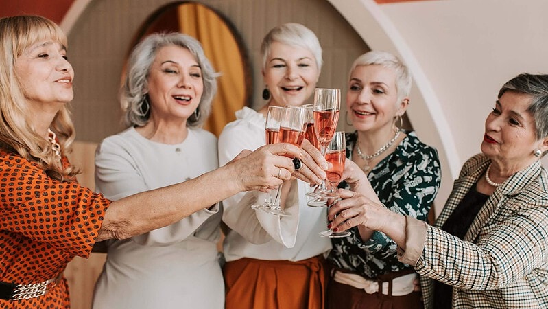 Fünf Frauen trinken gemeinsam Rosewein und feiern