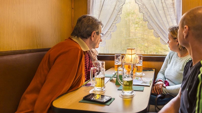 Personen gucken aus dem Zugfenster beim Braumeisters Dampfzug durch das Weißeritztal