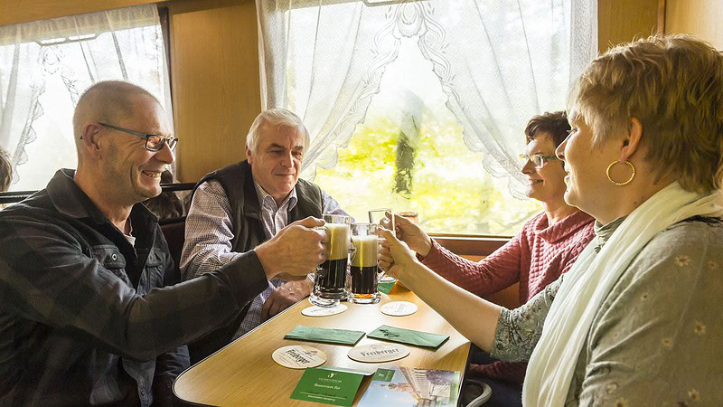 Personen stoßen mit Bier beim Braumeisters Dampfzug durch das Weißeritztal