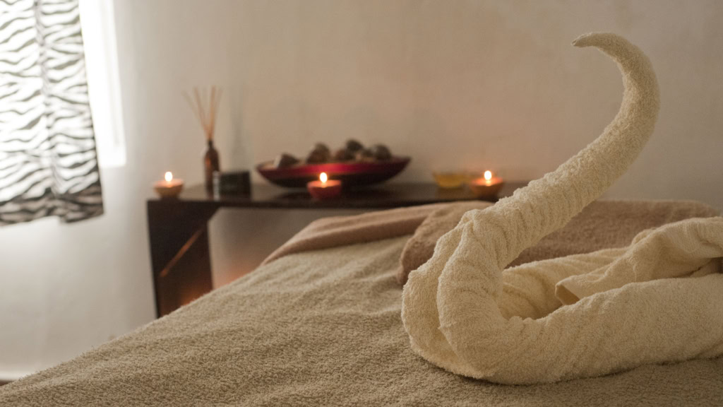Wellness_1600x900.jpg Handtuch zu einem Schwan gefaltet, Massageliege, Kerzen im Hintergrund