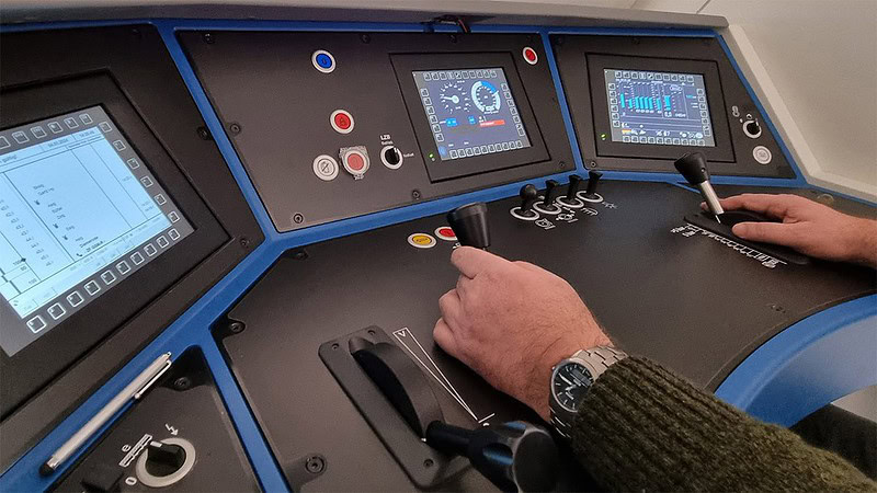 Eine Nahaufnahme des Bedienungspultes der Siemens Vectron. Ein Mann bedient die Schalter.