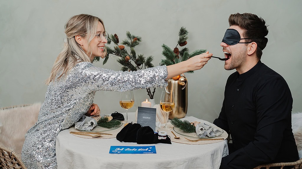blind-verkostung-dinner Paar füttert sich mit dem Inhalten der Geschenkbox Dinner in the Dark
