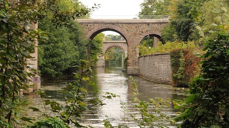 Fluss mit Büschen und Bogenbrücken