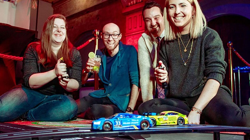 Gruppe von Freunden spiel mit Rennautos beim Party Game in Bottrop