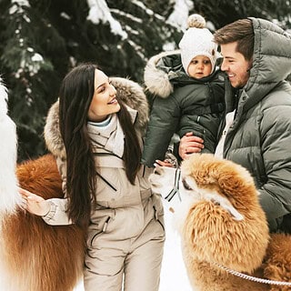 Eltern mit einem kleinen Kind posieren für ein Foto mit einer Alpaka