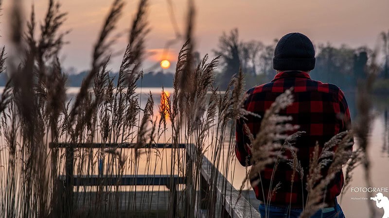 Eine Fotografie, die einen Mann am See darstellt